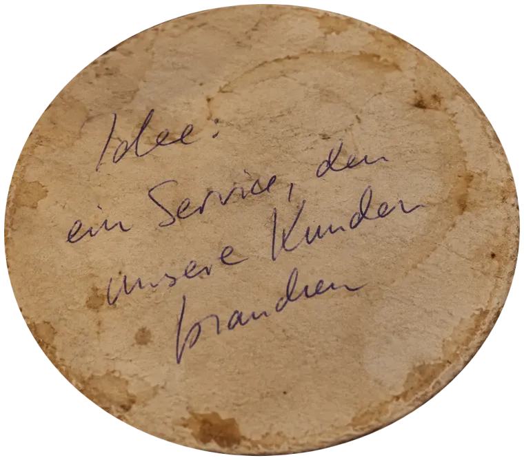 Alter, fleckiger Bierdeckel mit der handschriftlichen Notiz: Idee: ein Service, den unsere Kunden brauchen